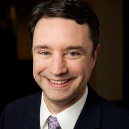 Brian Ellison smiles at the camera. Shown from the shoulders up, he wears a blue suit.